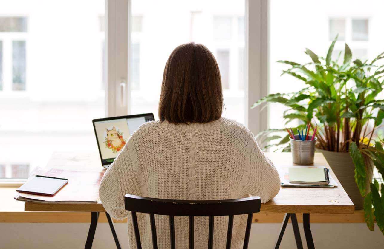 Femme vue de dos travaillant sur son bureau avec PC
