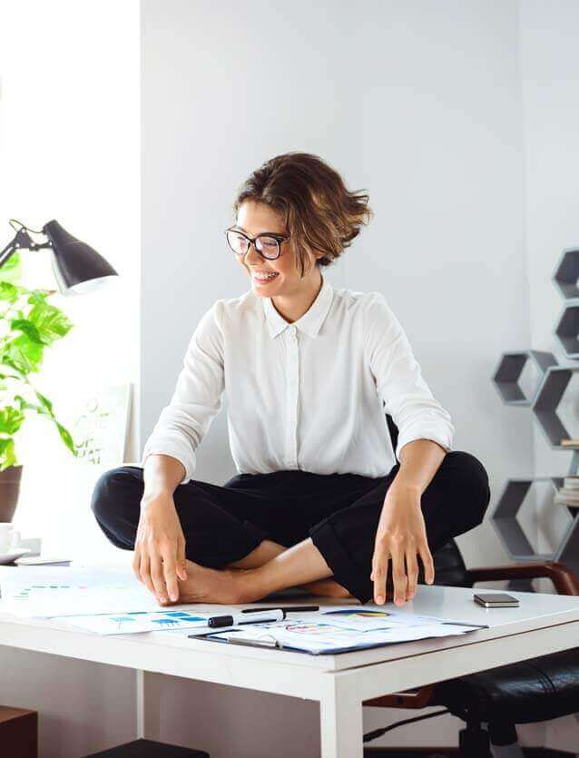 Photo d'une femme souriante assise en tailleur son bureau